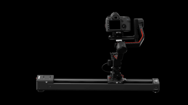 A digital camera mounted on a sleek, black motorized slider and gimbal setup against a dark background. The equipment features red accents and control buttons, designed for smooth and precise camera movements in videography or photography.